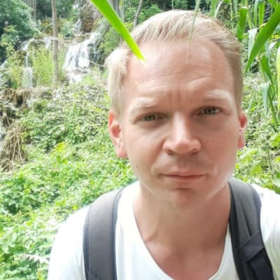 Tomi Lempinen i vit skjorta i en tropisk skog. 