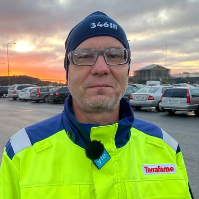 Jukka Vetola, huvudförtroendeman för arbetstagarna på Terrafame ser in i kameran. Han har på sig en gul rock och en blå mössa.