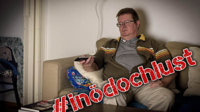 En man sitter i soffan och tittar på tv.