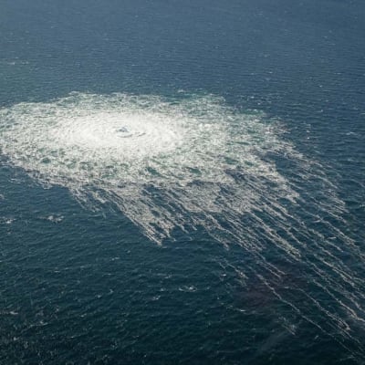 Ett flygfoto av ett runt område i havet som är alldeles vitt av bubblor från en undervattensläcka. Runt den vita rundeln bildas dessutom som en krans av bubblor.