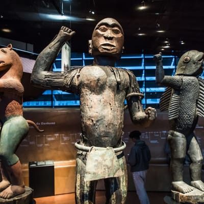 Kolme patsasta, joista yhdellä on kalan vartalo ja ihmisen käden ja jalat.