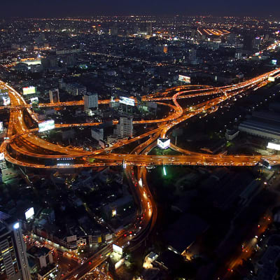 Thaimaan liikennettä yöaikaan. Pikaväylät loistavat oransseina katuvalojen lämpimästä valosta. Myös muualla kaupungissa on runsaasti valopisteitä.