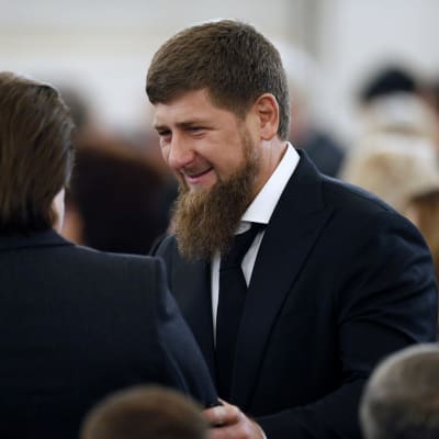 Kadyrov kättelee kameraan selin olevaa miestä. Kadyrovilla on musta puku, valkoinen kauluspaita ja musta kravatti. Ympärillä näkyy juhlaväkeä.