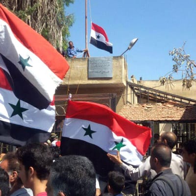Syyrialaiset miehet heiluttavat Syyrian lippuja Tafaksen kaupungissa, Daraan maaseudulla.