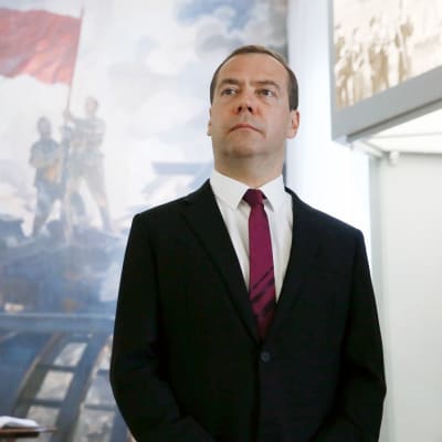 Dmitri Medvedev seisoo seinämaalauksen edessä Smolenskin alueen sotamuseossa ja katsoo kuva-alalla yläoikeaan. Maalauksessa neuvostosotilaat pystyttävät punalippua talon katolle sodasta kärsineessä kaupunkimaisemassa.