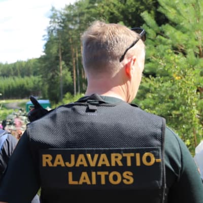 Två gränsbevakare och en polis står bredvid en bil.