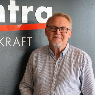 En medelålders man står framför en svart vägg. På väggen står det med vit text Posintra framtidskraft.