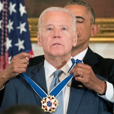 Kuvassa Obama seisoo Bidenin takana ja kiinnittää mitalia tämän kaulaan. Biden katsoo eteensä. Kyynel kimmeltää silmässä.