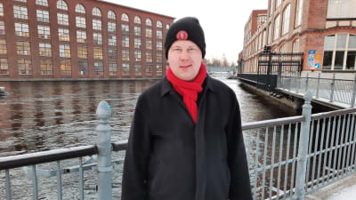 Petri Rajala står vid Tammerkoski i Tammerfors. I bakgrunden ser man forsen.