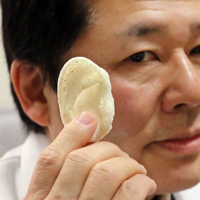 Professori Tsuyoshi Takato esittelee ryhmänsä 3D-tulostimella valmistamaa korvaproteesia.