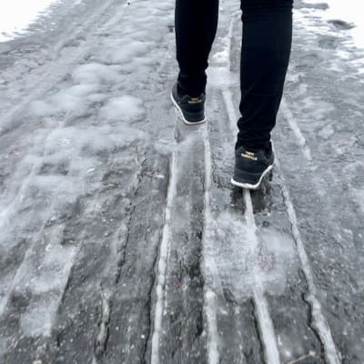 En person går med skor på en isig väg.