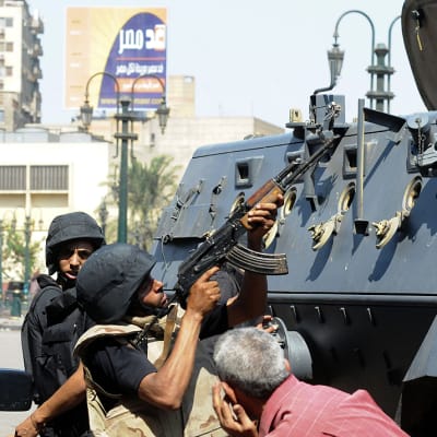 Egyptin turvallisuusjoukkojen sotilaat suojautuvat panssariajoneuvon taakse ja vastaavat al-Fateh-moskeijan minareettiin piiloutuneen sala-ampujan tulitukseen.