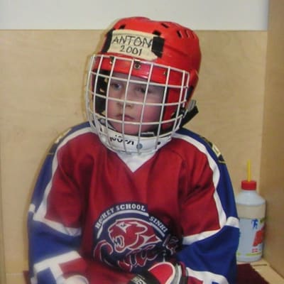 Anton Lundell som cirka femåring. Sitter i omklädningsrummet med hockeyutrustning.