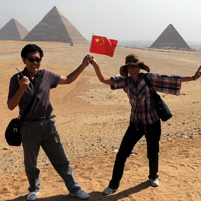Kiinalainen turistipariskunta poseeraa Gizan pyramidien edustalla.