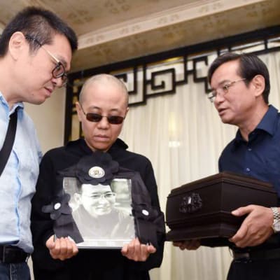 Liu Xia pitää käsissään miehensä muistokuvaa hautajaisten yhteydessä.