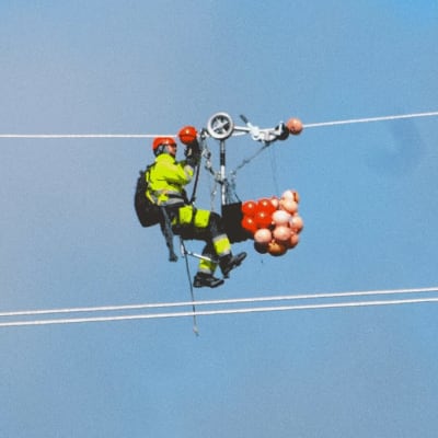 En servicearbetare hänger i en högspänningsledning.