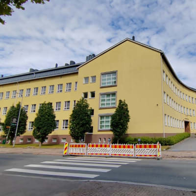 Iso keltainen koulurakennus kuvattuna jalkakäytävältä.