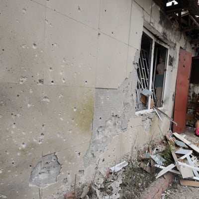 Nainen katsoi pommitusten tuhoja talonsa edessä Maryinkan kylässä, Donetskin lähellä lauantaina.