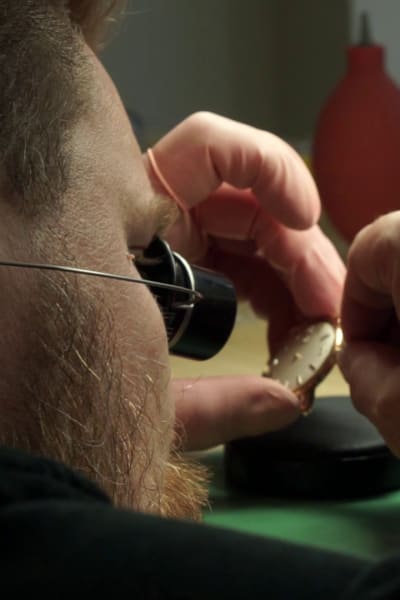 Närbild av en en urmakare som reparerar en klocka