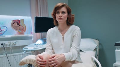 På bilden syns Liv Mjönes (Carro) sitta i en gynekologstol.
