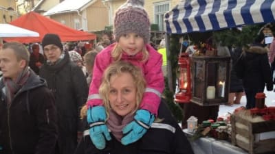 Ulrika Ström med sin dotter på axlarna på en marknad.