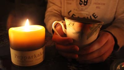 En kopp varm dryck och ett brinnande ljus.