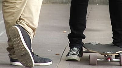 Två par fötter på en gård. En av personerna har en skateboard.  