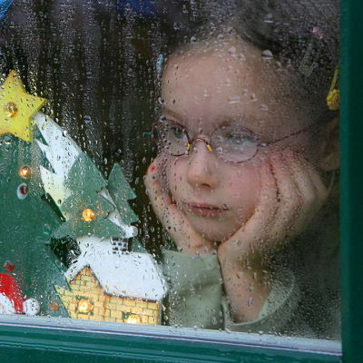 Lapsi katsoo sateisen ikkunan lävitse.