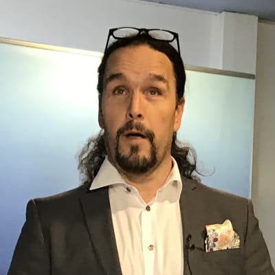Fredrik Karlström står vid ett högt bord med en mikrofon framför sig.