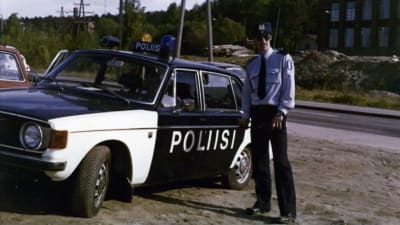 Thomas Elfgren seisoo poliisiasussa poliisiauton vieressä poliisikokelaskurssin aikaan Tampereella vuonna 1976. Poliisiautona Volvo, kesäaika.