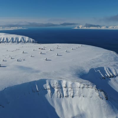 Kuvassa näkyy tutkapalloja Huippuvuorilla jäätikön päällä, taustalla näkyy merta.