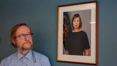 Estlands Helsingforsambassadör Harri Tiido tittar på ett porträtt av den estniska presidenten Kersti Kaljulaid.