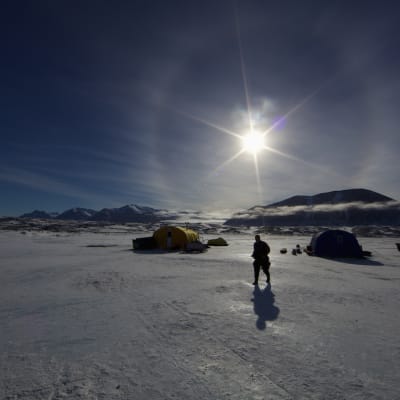 Ett tält och en man i Antarktis. Solen skiner. 