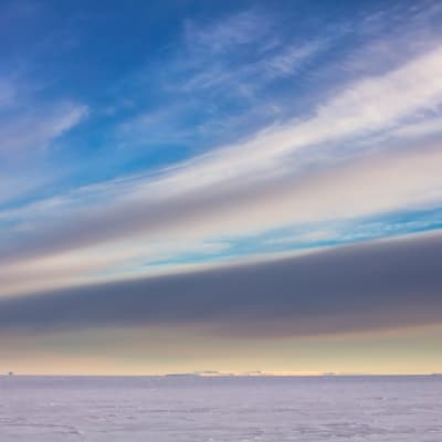 Pastellfärgade moln över isen i Antarktis.