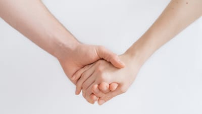 En bild av en mans och en kvinnas händer som håller i varandra.
