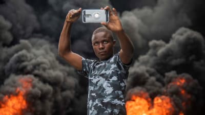 En demonstrant tog en selfie mot bakgrunden av brinnande bildäck i Port-au-Prince på söndagen. 