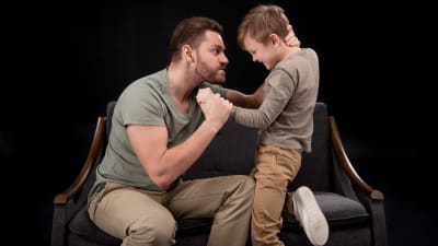 en pappa är arg och tar hårt i sin sons nacke och hand