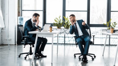 Två män i kostym sitter och skvallrar i modernt kontorsutrymme