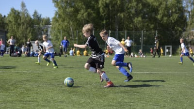 En spelare från SJK springer i kapp med en spelare från Kuffen under ett anfall under en fotbollsmatch.