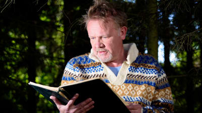 Sagofarbrorn Mårten Holm läser en bok i skogen.