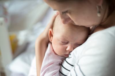 Mamma håller baby mot sitt bröst.