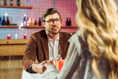 Man med glasögon sitter på en restaurang tillsammans med en kvinna som har ryggen mot kameran