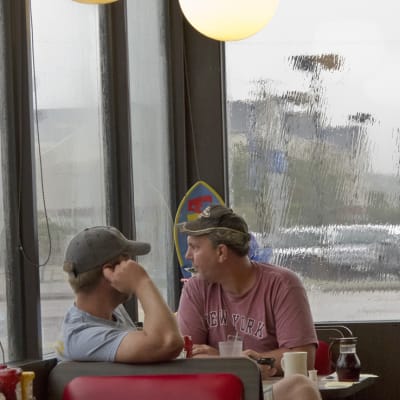 Miehet pitävät sadetta kahvilassa
