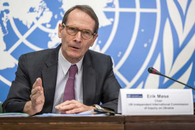 Erik Møse sitter vid ett skrivbord och talar medan han gestikulerar med händerna. I förgrunden syns en namnskylt med hans namn på och en mikrofon.