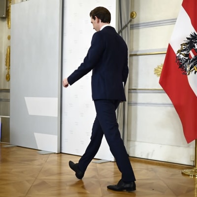Österrikes före detta förbundskansler går ut genom dörr.