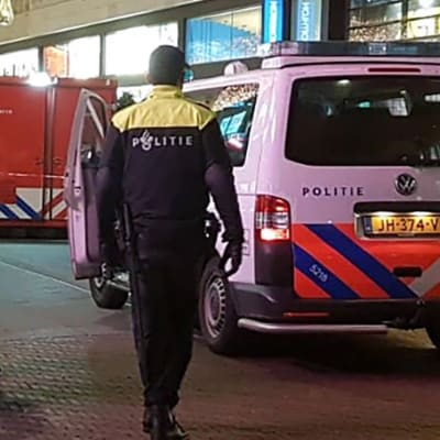 Tre poliser bredvid en polisbil på shoppinggatan i Haag där knivdådet ägde rum.