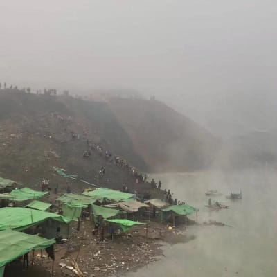 Människor tittade på medan räddningsarbetare gav sig ut på sjön i Hpakant-komplexet för att leta efter offer för jordskredet.  Bilden tagen onsdagen 22.12. 