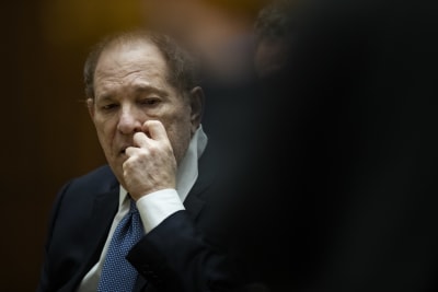 Harvey Weinstein kliar sig i ansiktet medan han tittar ner. Han sitter i en rättssal.