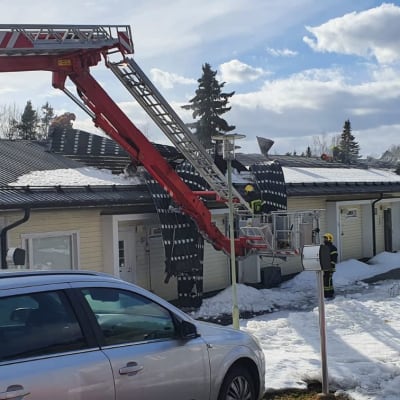 Palokunta avaa rivitalon kattoa paloauton tikkaiden avulla.
