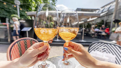 Två vinglas med orange dricka i skålas mot varandra vid restaurang Teatteri.